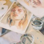 A collection of artistic watercolor portraits showcasing vibrant creativity on a glass table.